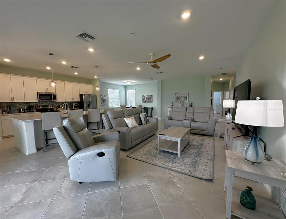 An open-concept living room and kitchen featuring light gray tile flooring and neutral furniture — 4835 BIRCHWOOD COURT UNIT 6222, PUNTA GORDA, FL