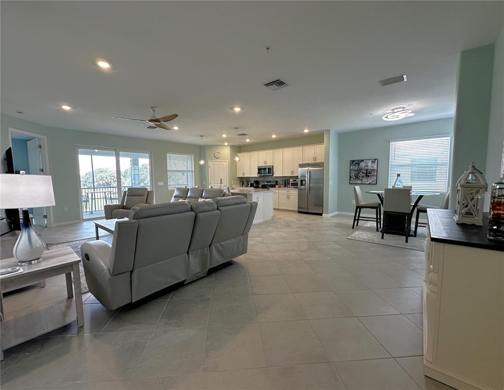 An open-concept living and dining area features light gray tile floors and white kitchen cabinetry — 4835 BIRCHWOOD COURT UNIT 6222, PUNTA GORDA, FL