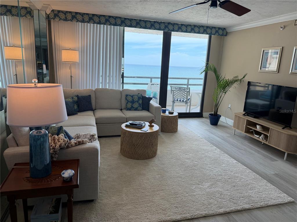 A living room features a sectional sofa, a rug, and a balcony overlooking the ocean — 3855 S ATLANTIC AVENUE UNIT 702, DAYTONA BEACH, FL