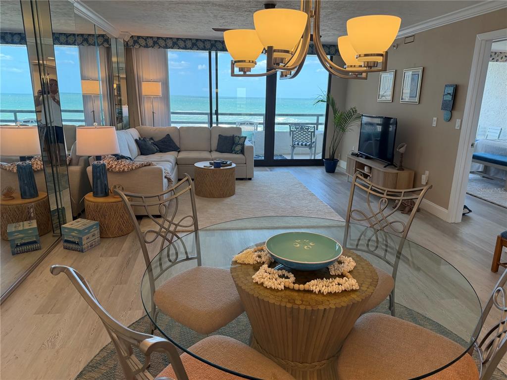 A dining area with a glass table overlooks a living room and a balcony with ocean views — 3855 S ATLANTIC AVENUE UNIT 702, DAYTONA BEACH, FL
