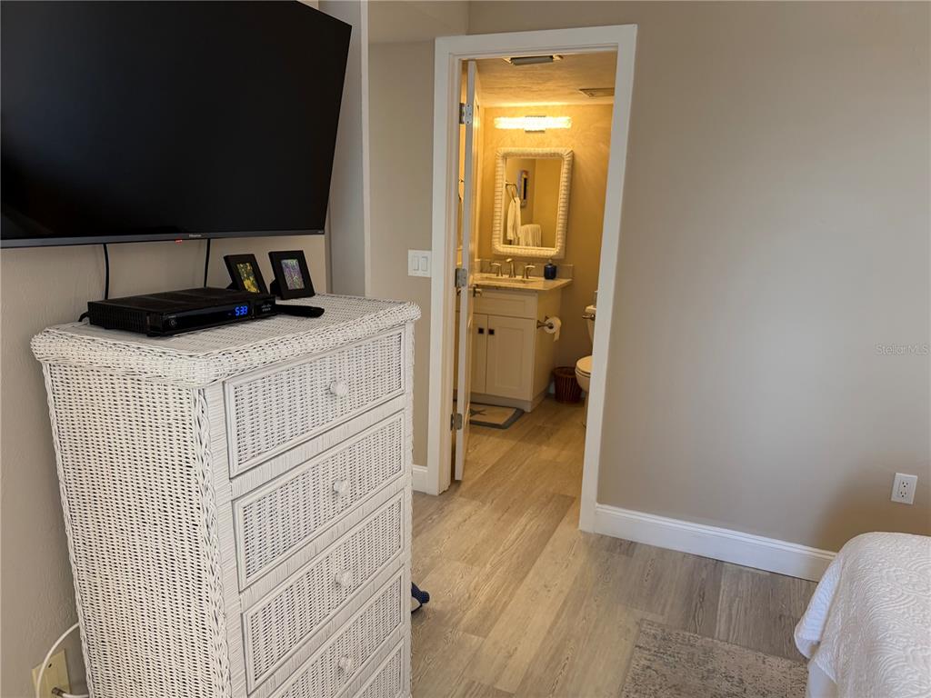 A white wicker dresser stands in a bedroom with a view into an adjacent bathroom — 3855 S ATLANTIC AVENUE UNIT 702, DAYTONA BEACH, FL