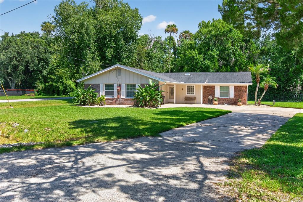 A single-story brick and siding house with a concrete driveway and lush green lawn — 2420 HAZEL BISHOP DRIVE, NEW SMYRNA BEACH, FL