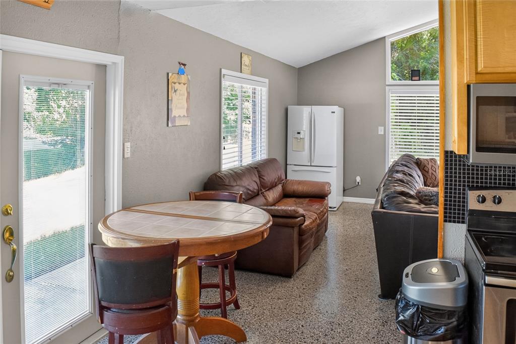 A kitchen and living area features a round dining table, leather sofa, and refrigerator — 2420 HAZEL BISHOP DRIVE, NEW SMYRNA BEACH, FL