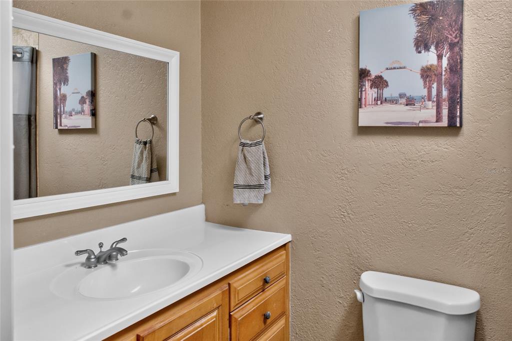 A bathroom features a white vanity, a mirror, a towel ring, and wall art — 2420 HAZEL BISHOP DRIVE, NEW SMYRNA BEACH, FL