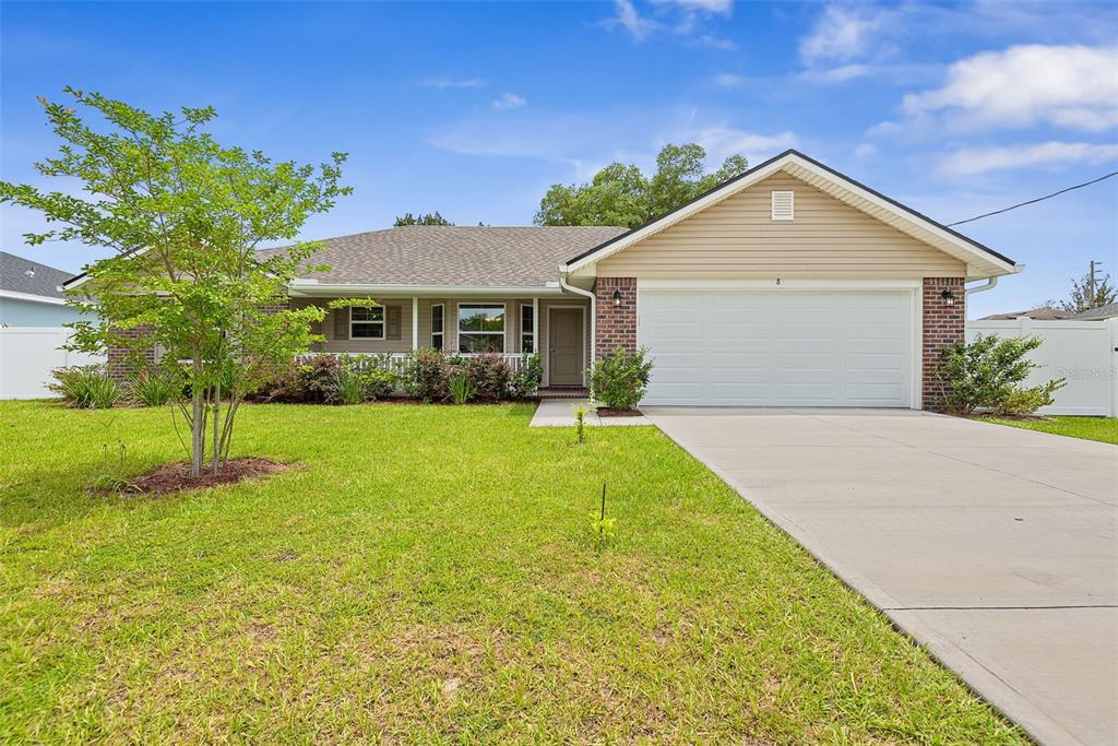 A single-story house with a tan exterior, brick accents, and a two-car garage — 8 PERSIMMON DRIVE, PALM COAST, FL