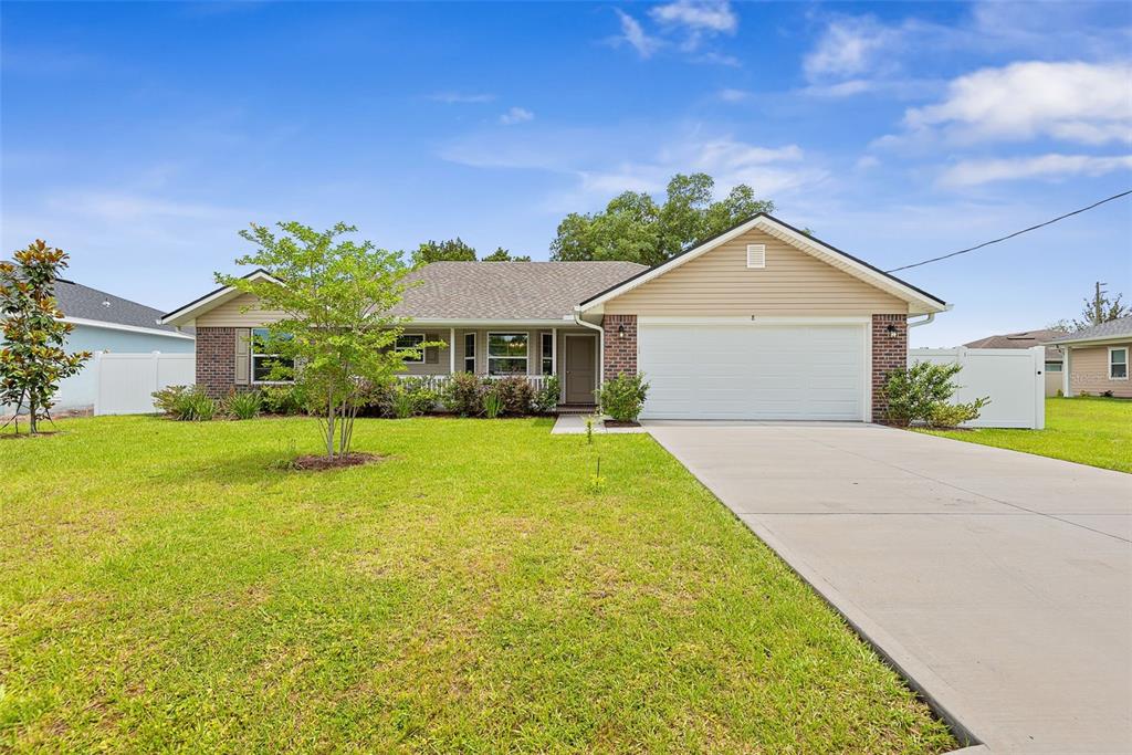 A single-story house with a brick and tan siding exterior, a driveway, and a lawn — 8 PERSIMMON DRIVE, PALM COAST, FL