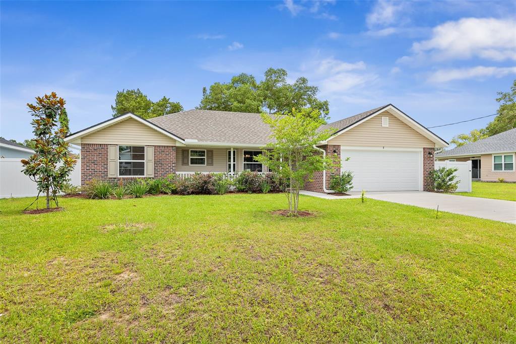 A single-story house with a brick and tan siding exterior, a garage, and a lawn — 8 PERSIMMON DRIVE, PALM COAST, FL