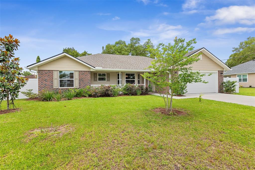 A single-story house with tan siding, brick accents, a front porch, and a two-car garage — 8 PERSIMMON DRIVE, PALM COAST, FL