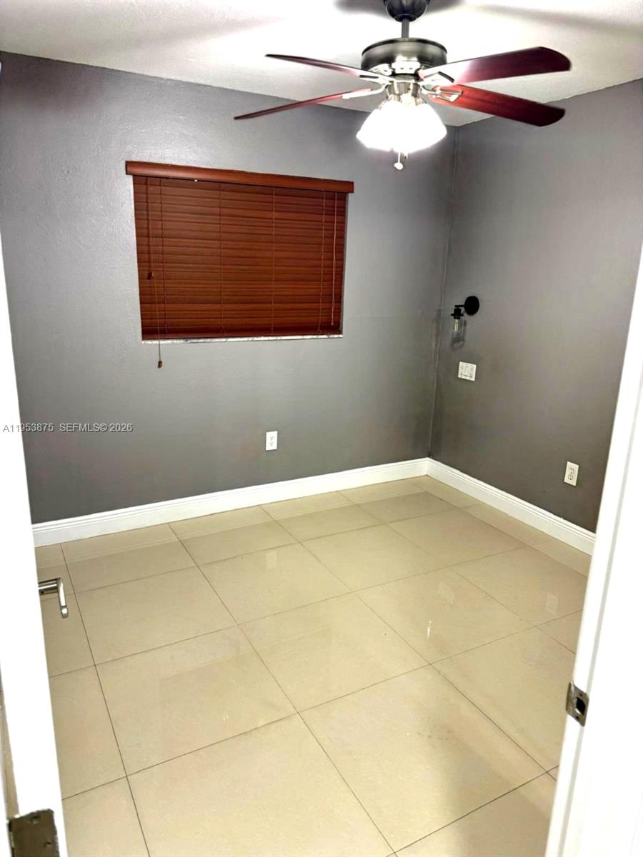 An empty room features gray walls, tile flooring, a ceiling fan, and a window blind — 5461 W 24th Ave # 25, Hialeah FL 33016, HIALEAH, FL
