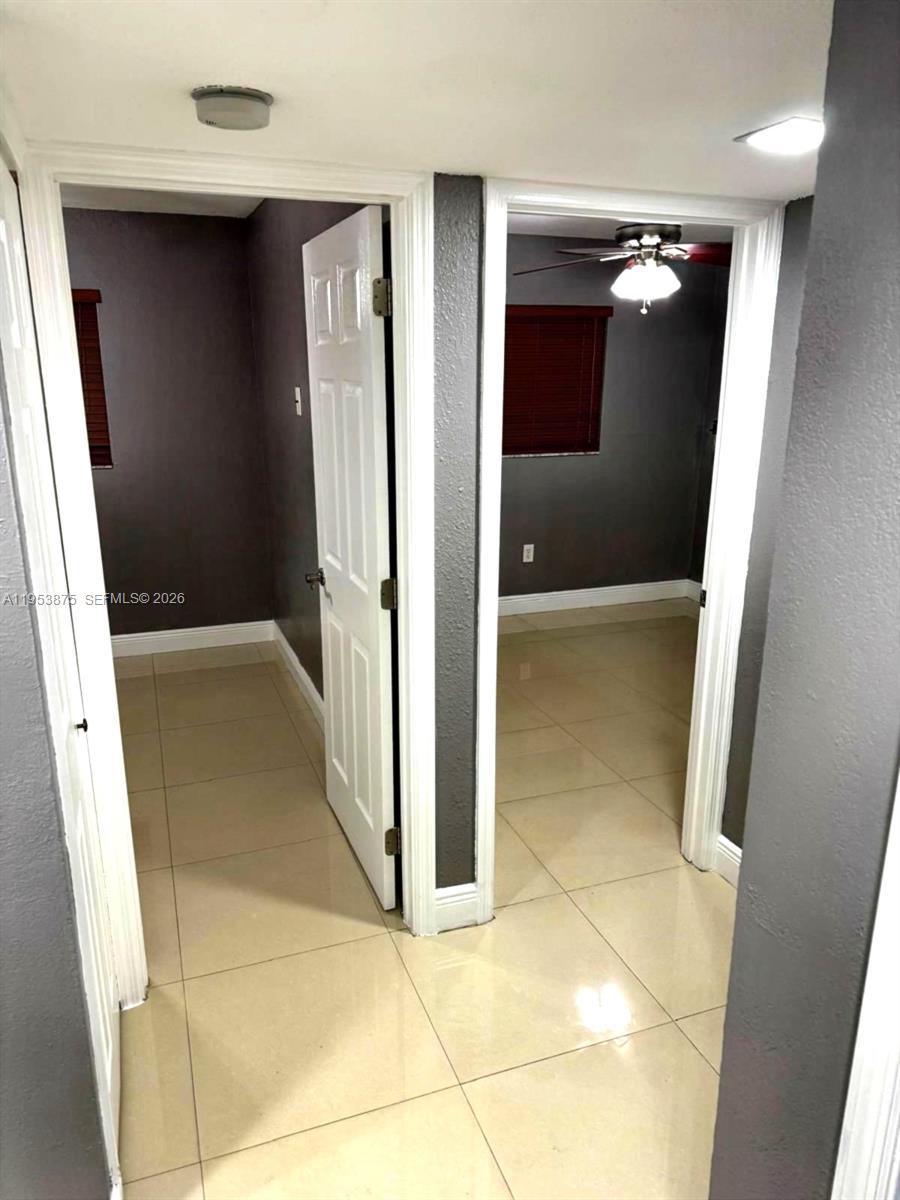 A hallway with light-colored tile floors leads to two doorways opening into dark-walled rooms — 5461 W 24th Ave # 25, Hialeah FL 33016, HIALEAH, FL