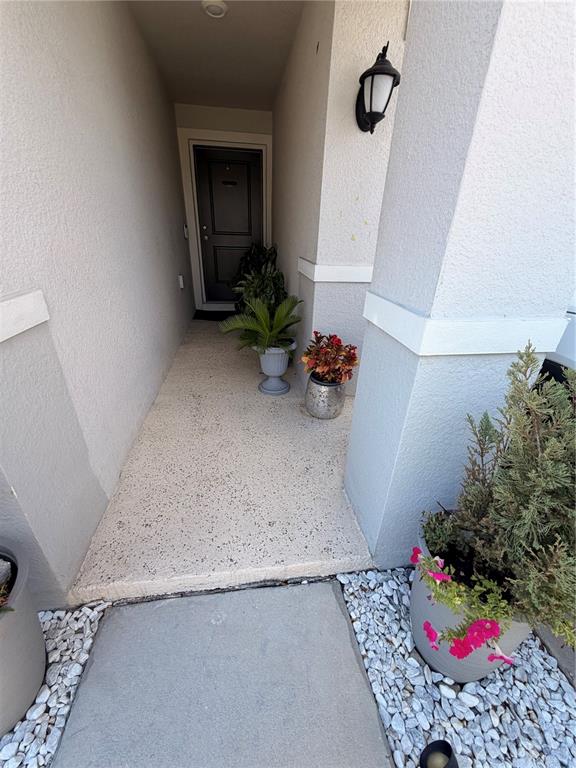 A covered entryway features a concrete floor, potted plants, and a dark front door — 9051 OSCRAFT DRIVE, DAVENPORT, FL