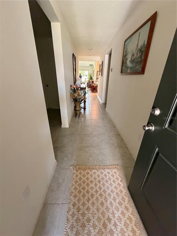 A tiled hallway leads from an open doorway toward a distant room with bar stools — 9051 OSCRAFT DRIVE, DAVENPORT, FL