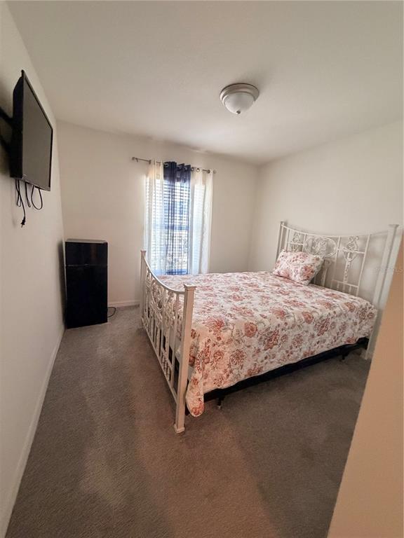 A bedroom features a white metal bed frame, a floral quilt, and a wall-mounted television — 9051 OSCRAFT DRIVE, DAVENPORT, FL