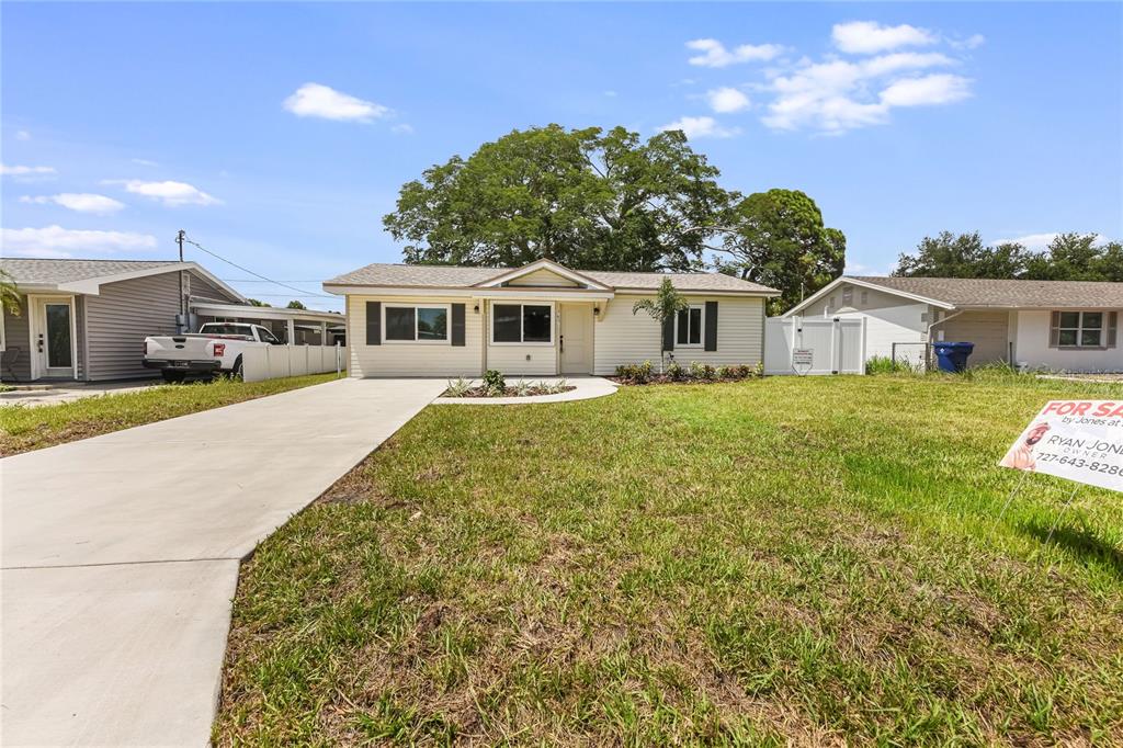 A single-story house with light-colored siding and a concrete driveway sits on a grassy lot — 7851 40 AVE N, ST PETERSBURG, FL
