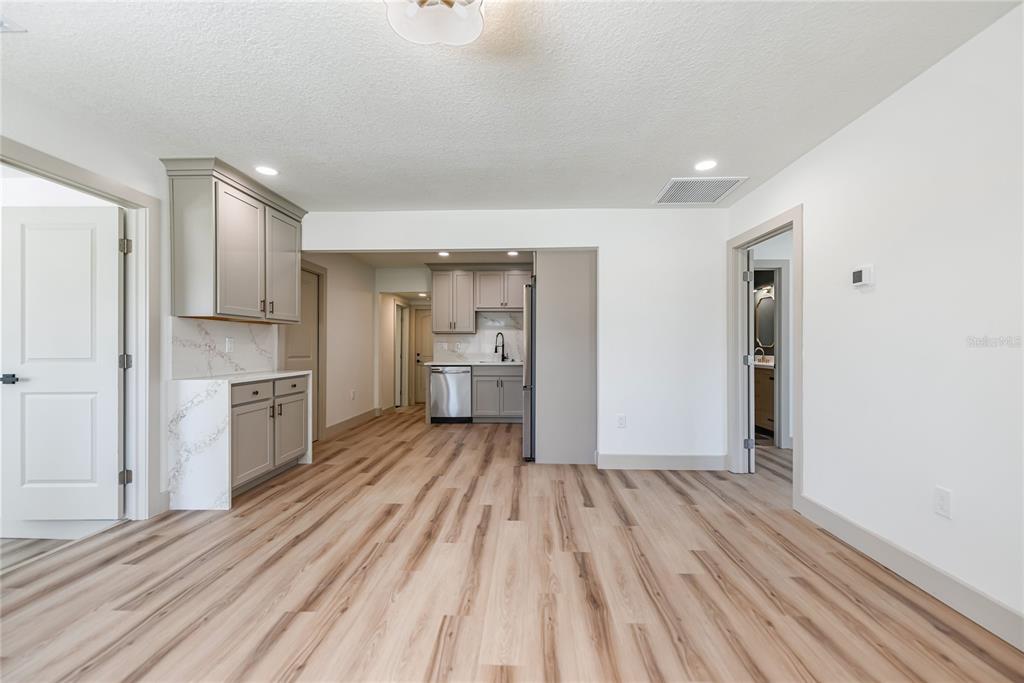 A kitchen and dining area with light wood-look flooring, gray cabinets, and white countertops — 7851 40 AVE N, ST PETERSBURG, FL