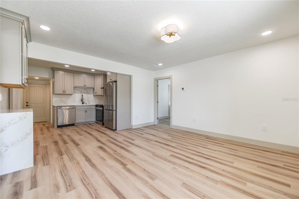 A kitchen with grey cabinets and stainless steel appliances opens into a spacious living area — 7851 40 AVE N, ST PETERSBURG, FL