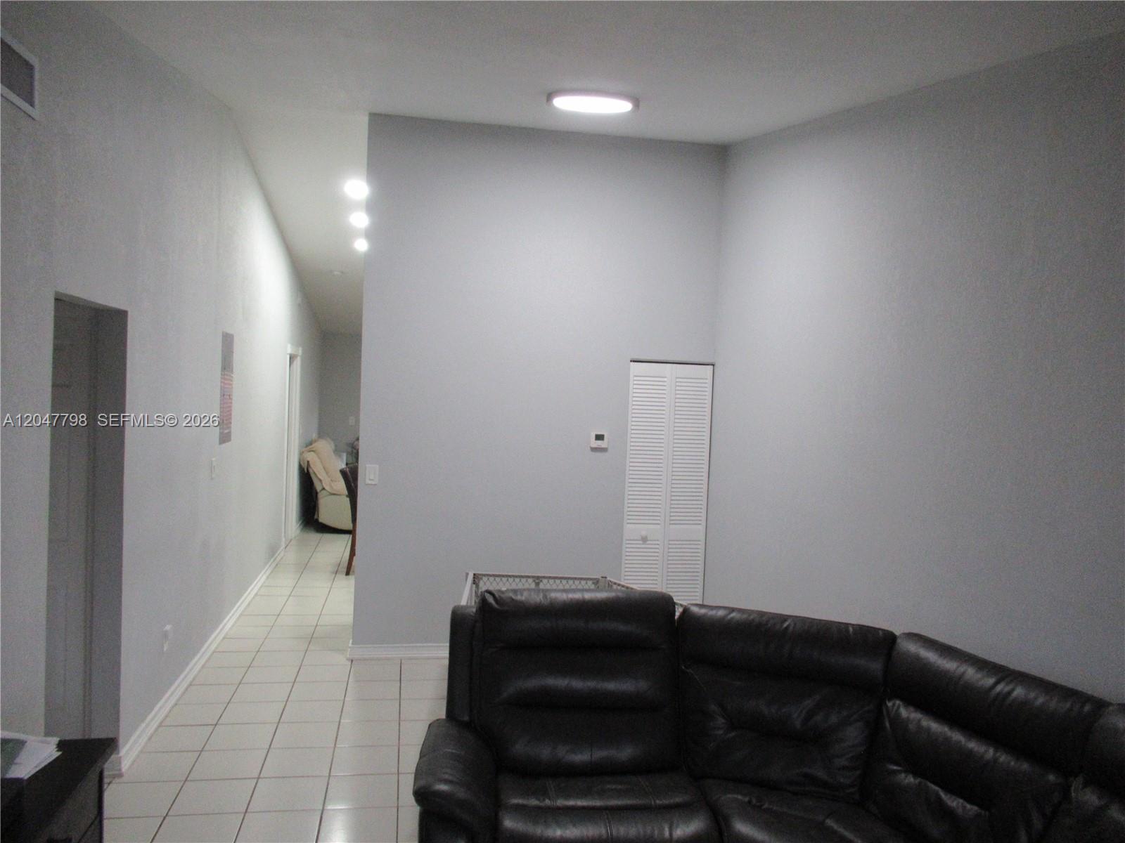 A living room features a dark leather sectional, light-colored tile flooring, and gray walls — 11530 NW 87th Ct, Hialeah Gardens FL 33018, HIALEAH GARDENS, FL