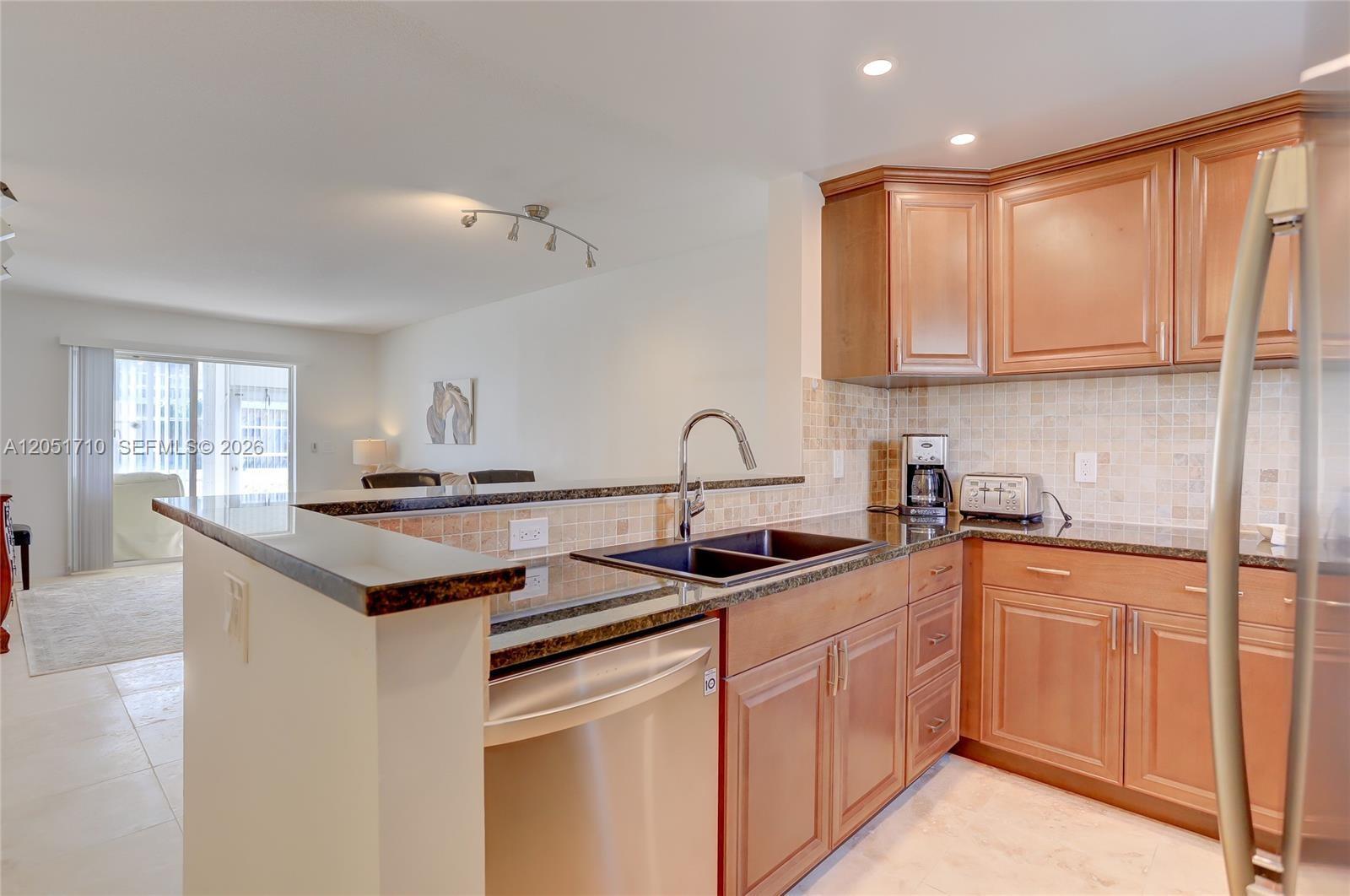 A kitchen features wood cabinets, dark granite countertops, stainless steel appliances, and a breakfast bar — 2212 NE 1st Way # 101, Boynton Beach FL 33435, BOYNTON BEACH, FL
