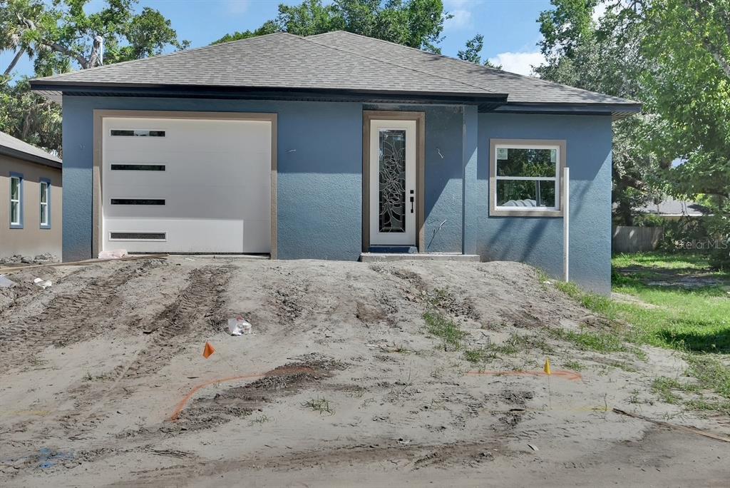A blue single-story house with a white garage door and a decorative glass front door — 558 WALLACE STREET, DAYTONA BEACH, FL