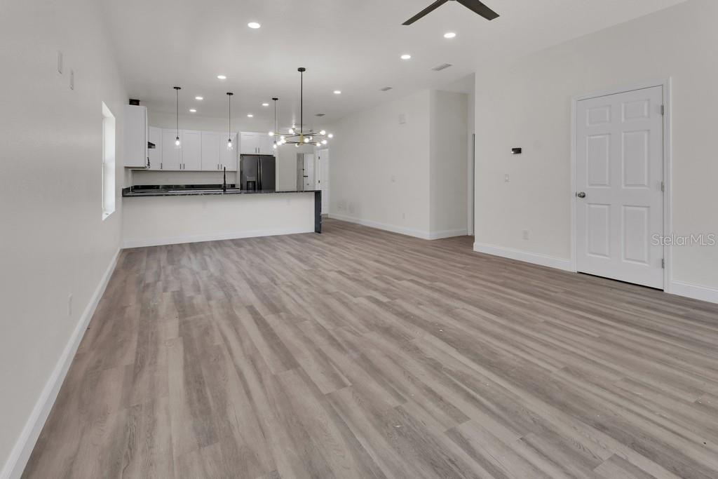An open-concept living area features light wood-look flooring, white walls, and a modern kitchen — 558 WALLACE STREET, DAYTONA BEACH, FL