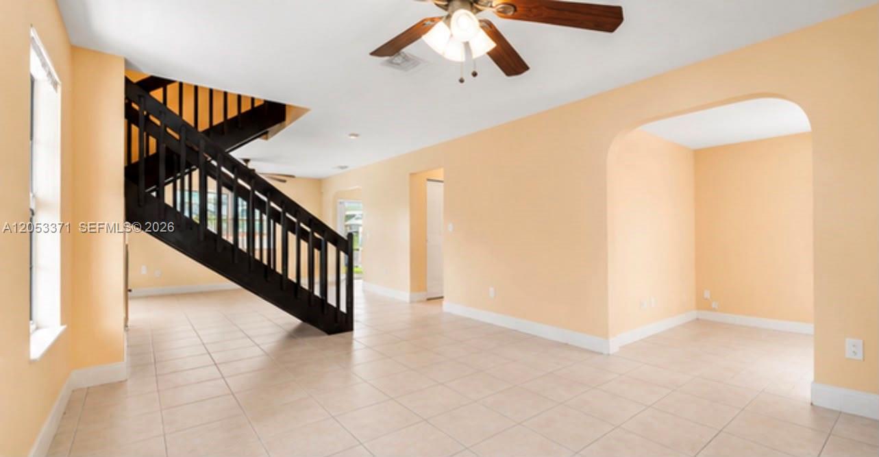 An interior view shows a living area with light-colored tile floors and a black staircase — MIAMI, FL