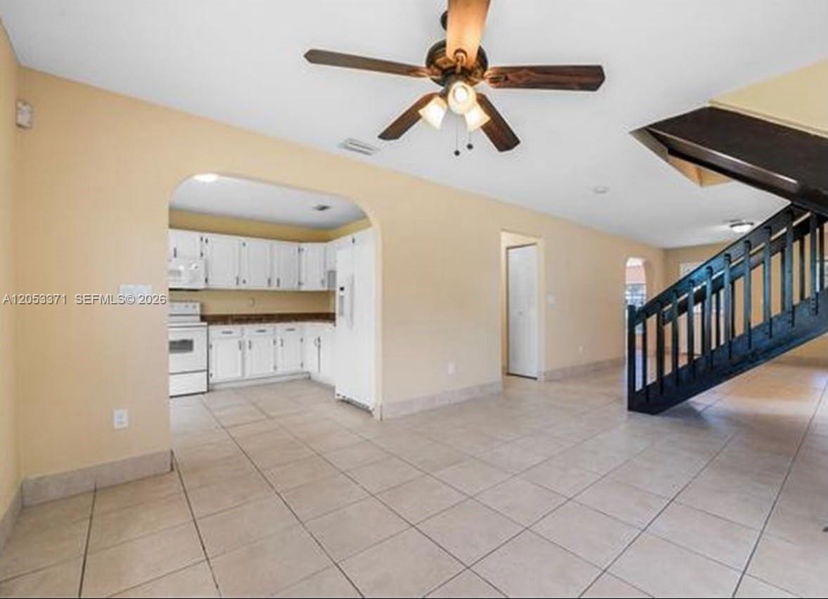 An open-concept living area features tile flooring, a ceiling fan, and an adjacent white kitchen — MIAMI, FL