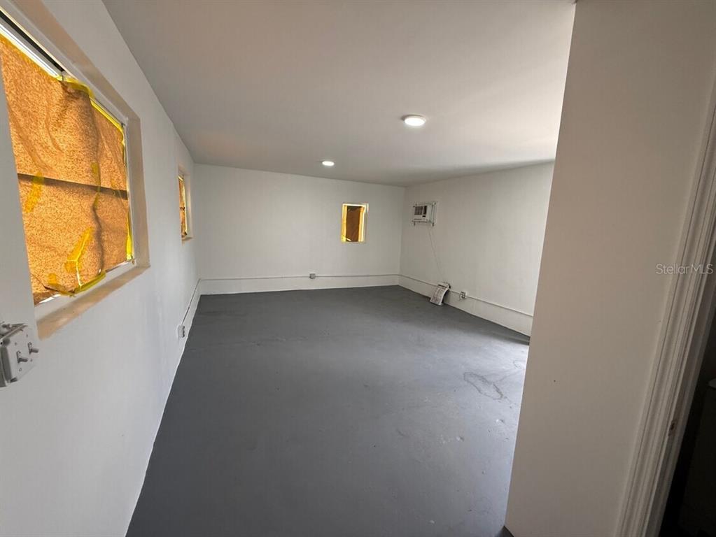 An empty room with white walls, a gray floor, and two windows covered in paper — 14040 NW 19TH AVENUE, OPA LOCKA, FL