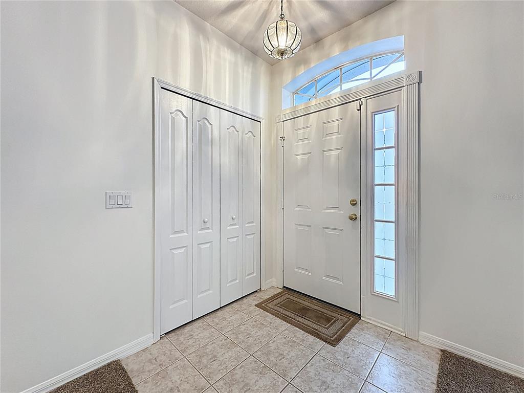 An entryway features a white front door with a sidelight, tile flooring, and a closet — 4246 NEWLAND STREET, CLERMONT, FL
