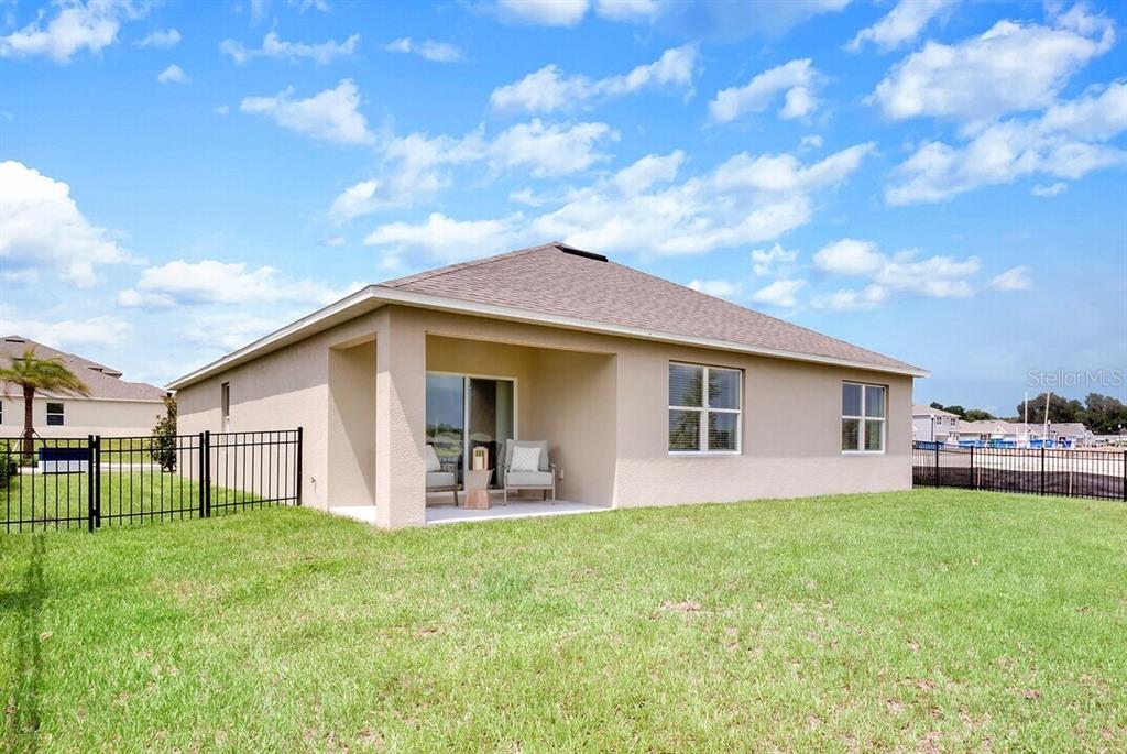 A kitchen with white cabinets and an island flows into a dining area with seating — 2607 HARRIER COURT UNIT Solstice, APOPKA, FL