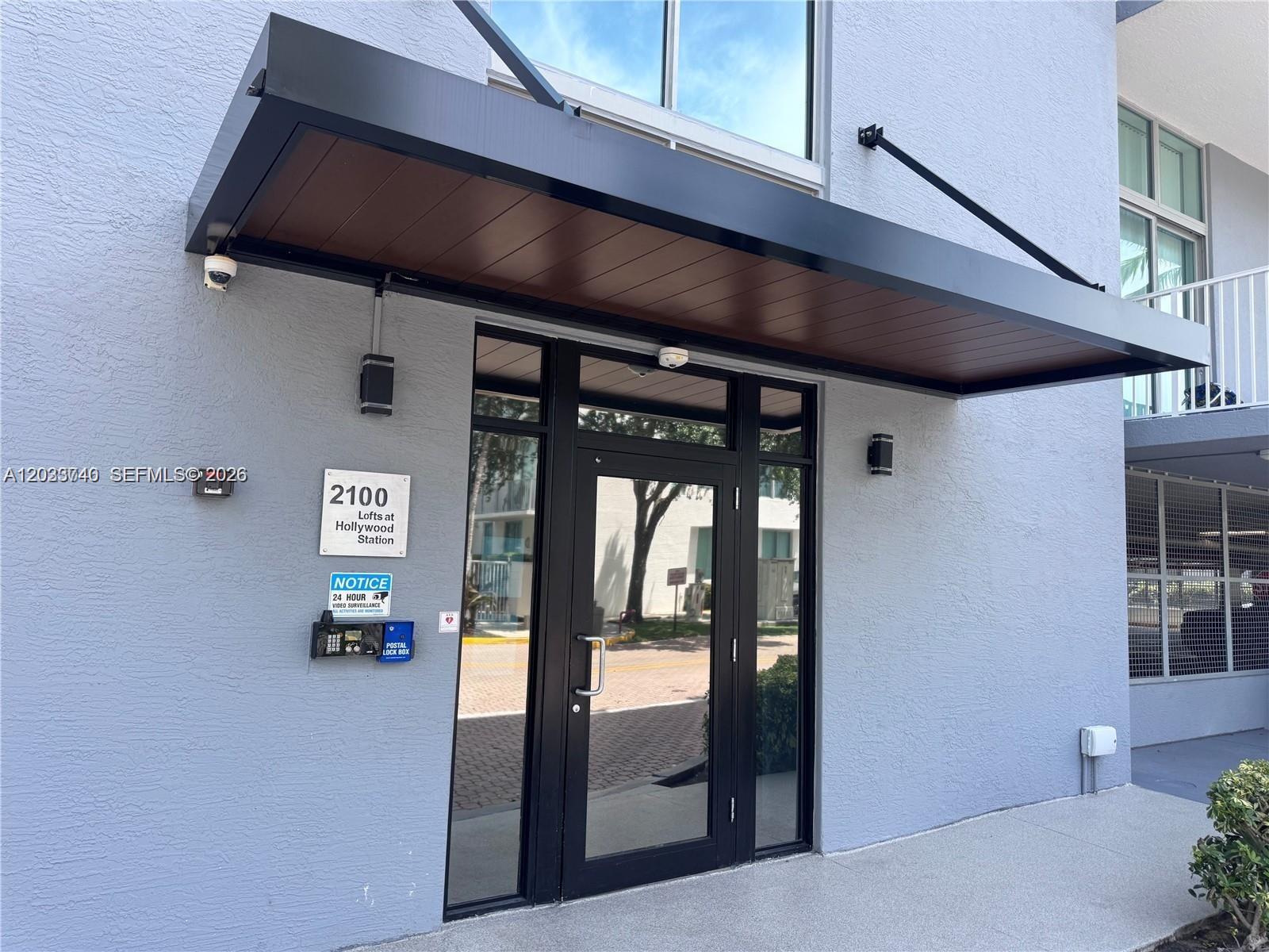 The exterior entrance of a building features a black metal awning over a glass door — 2100 Van Buren St # 322, Hollywood FL 33020, HOLLYWOOD, FL