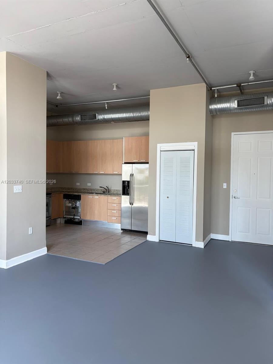 An open-concept kitchen with light wood cabinets, stainless steel appliances, and exposed industrial ductwork — 2100 Van Buren St # 322, Hollywood FL 33020, HOLLYWOOD, FL