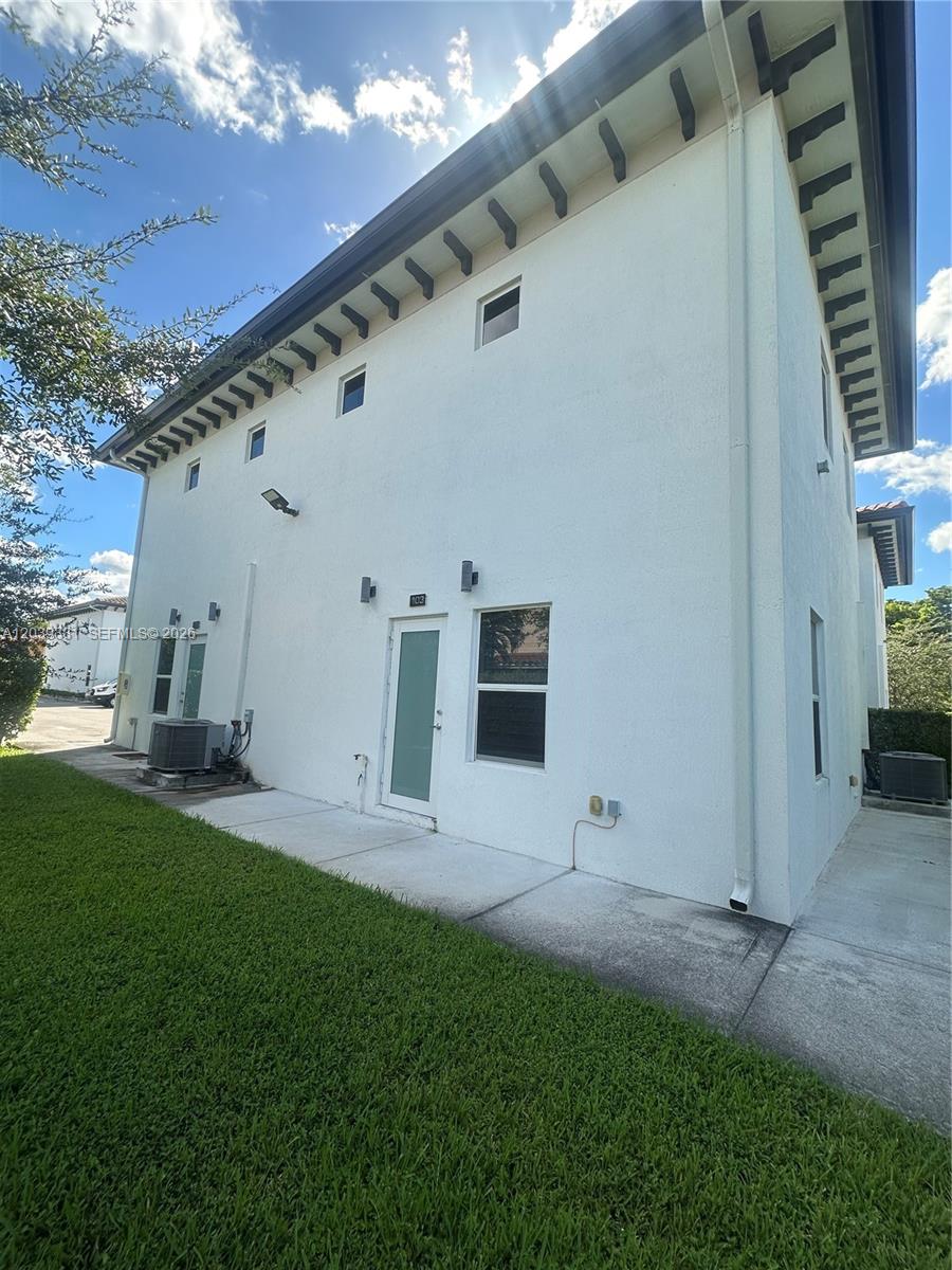 The exterior of a white multi-story building features a lawn, concrete walkway, and air conditioners — 6410 SW 139th Avenue Rd # 203, Miami FL 33183, MIAMI, FL