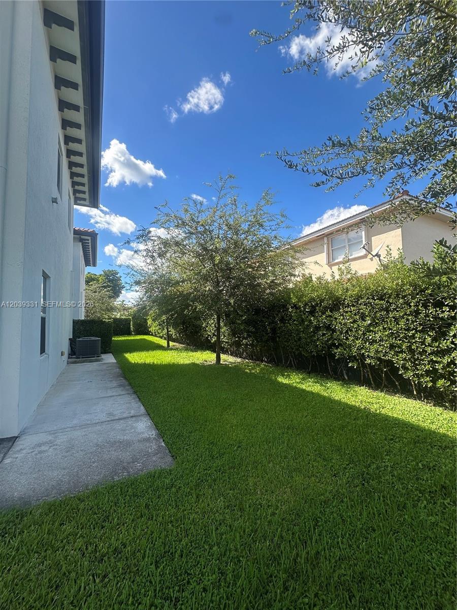 A side yard features a concrete walkway, green lawn, and a tall hedge — 6410 SW 139th Avenue Rd # 203, Miami FL 33183, MIAMI, FL
