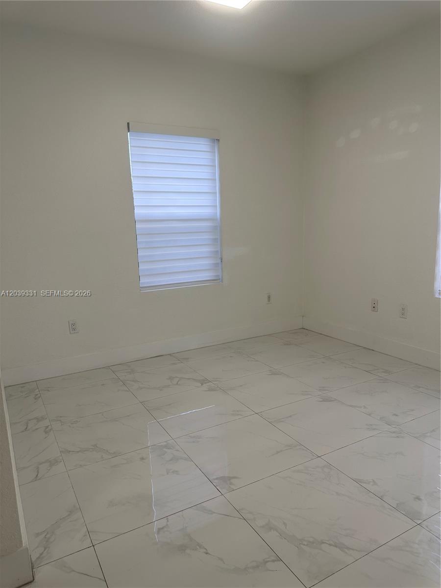 An empty room features white walls, light-colored marble-patterned tile flooring, and a window with blinds — 6410 SW 139th Avenue Rd # 203, Miami FL 33183, MIAMI, FL