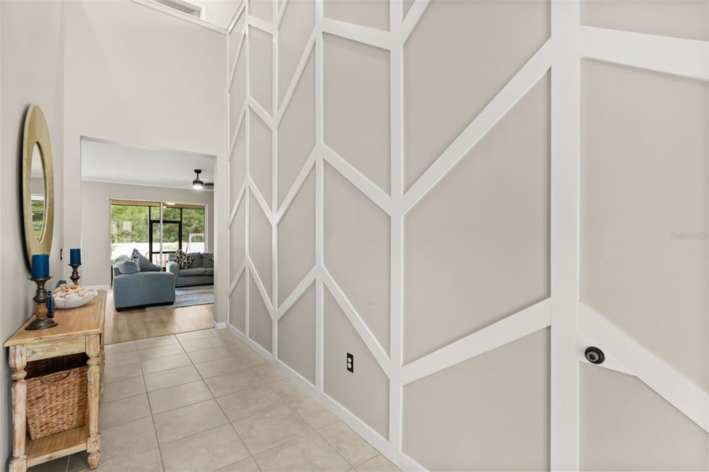 A hallway features a tall wall with white geometric trim and a light wood console table — 726 PORTER RYE AVENUE, DEBARY, FL