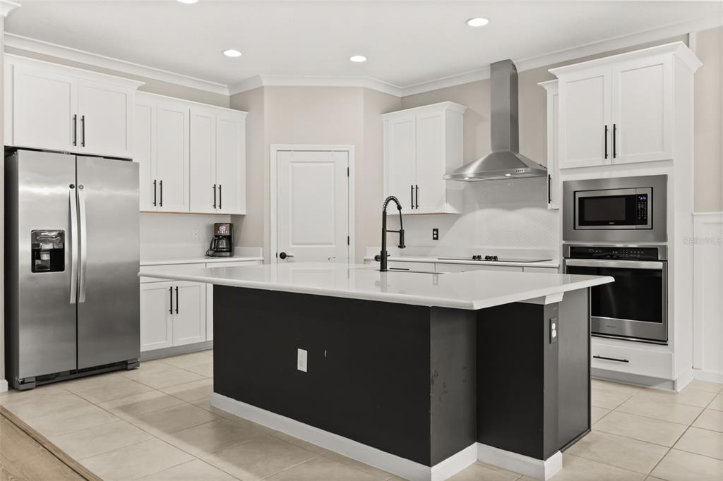 A kitchen features white cabinets, stainless steel appliances, a dark island, and light countertops — 726 PORTER RYE AVENUE, DEBARY, FL