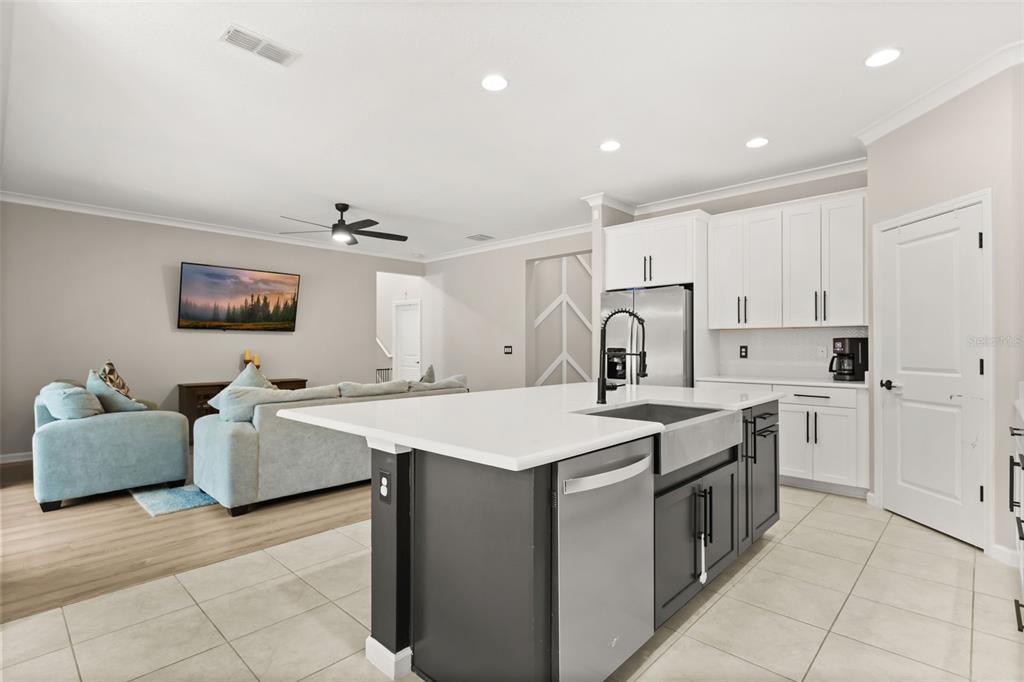 A kitchen with a dark island and white cabinets opens into a living room area — 726 PORTER RYE AVENUE, DEBARY, FL