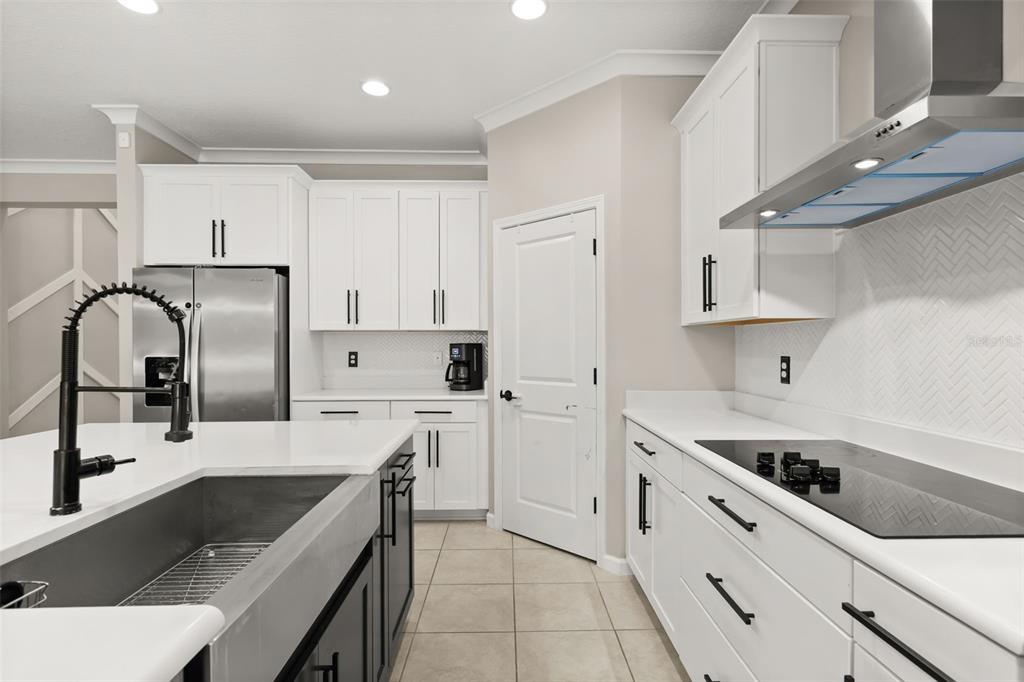 A modern kitchen features white cabinets, a large island with a farmhouse sink, and stainless appliances — 726 PORTER RYE AVENUE, DEBARY, FL