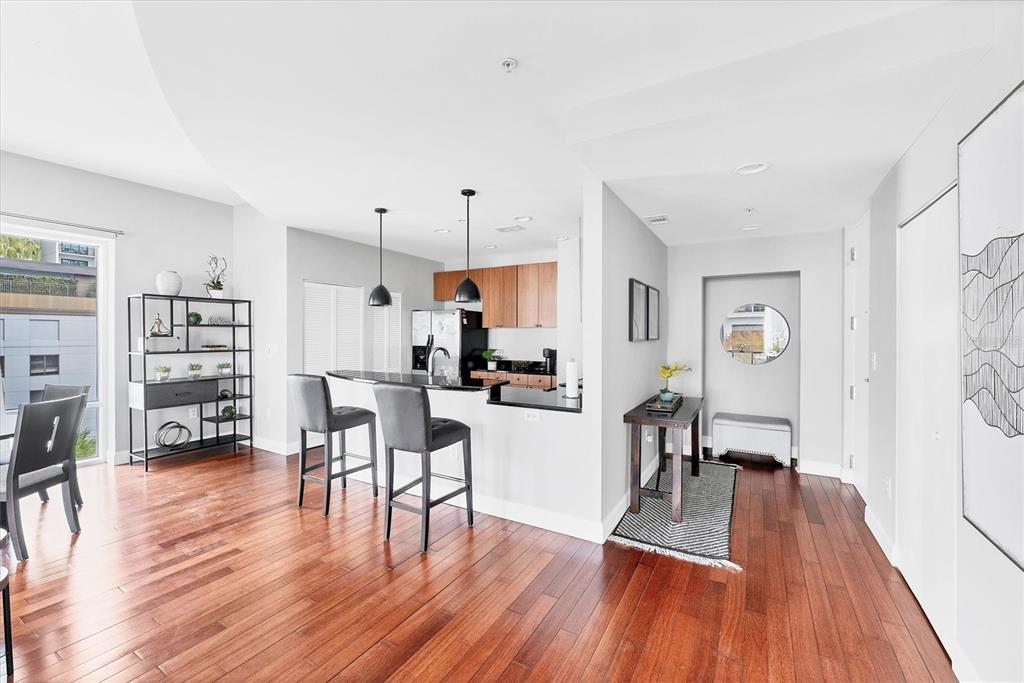 An open-concept kitchen with a breakfast bar overlooks a dining area with hardwood floors — 525 E JACKSON STREET UNIT 609, ORLANDO, FL