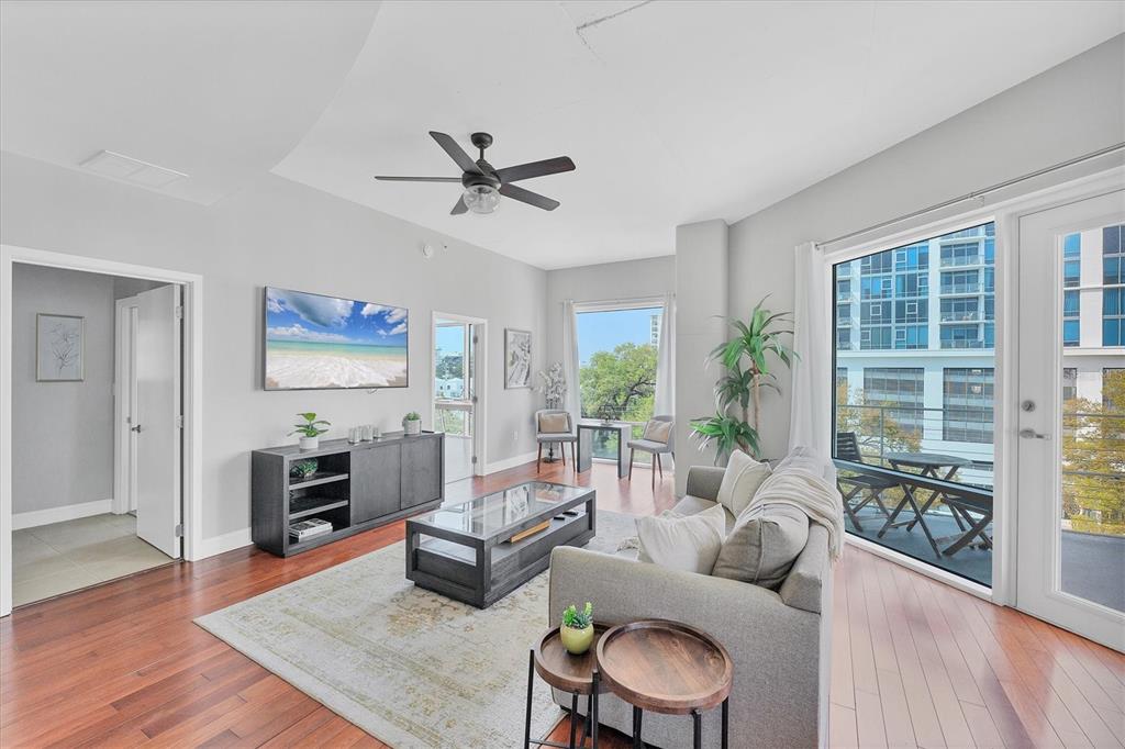 A modern living room features hardwood floors, a gray sofa, and a balcony with city views — 525 E JACKSON STREET UNIT 609, ORLANDO, FL