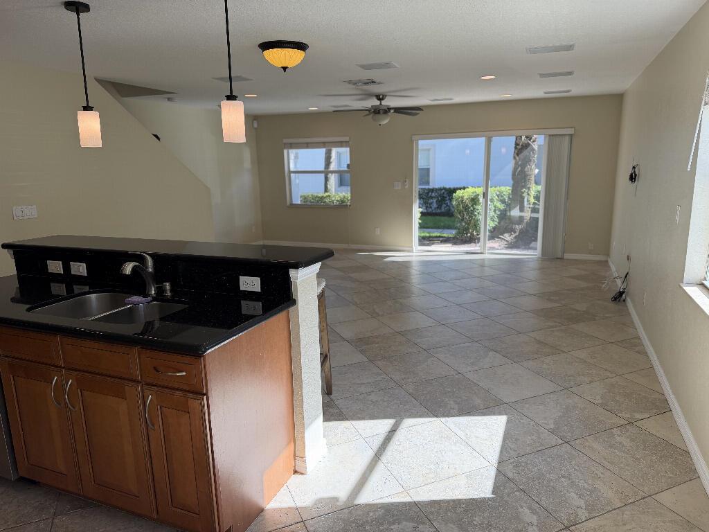 A kitchen with dark countertops and wood cabinets overlooks an open living area with tile — 22159 Majestic Woods Way, Boca Raton FL 33428, BOCA RATON, FL