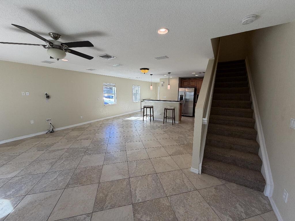 An open-concept living area features tile flooring, a kitchen island with bar stools, and stairs — 22159 Majestic Woods Way, Boca Raton FL 33428, BOCA RATON, FL