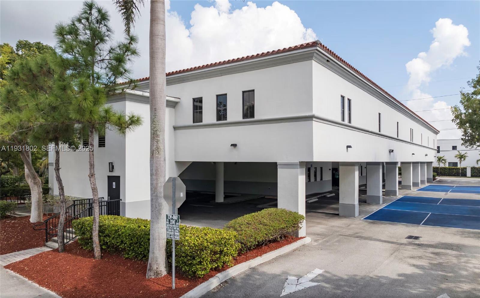 A two-story white commercial building features a ground-level covered parking area and landscaped bushes — 6900 SW 80th St, Miami FL 33143, MIAMI, FL