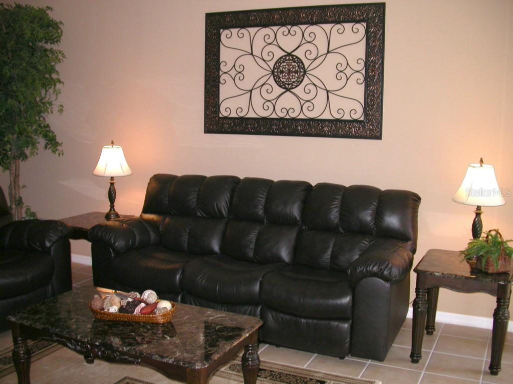 A living room features a black leather sofa, a marble coffee table, and wall art — 10313 HEBBLEWHITE COURT, ENGLEWOOD, FL