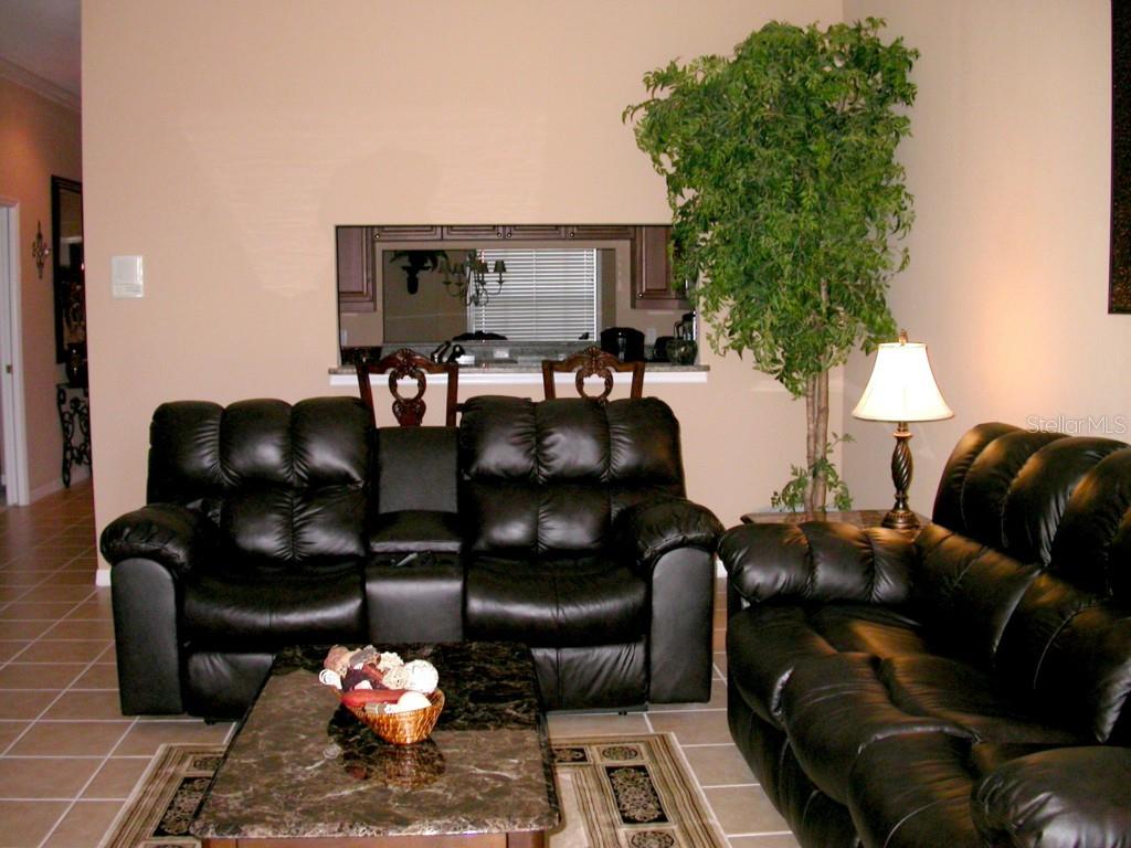 A living room features black leather sofas, a marble coffee table, and a large indoor plant — 10313 HEBBLEWHITE COURT, ENGLEWOOD, FL