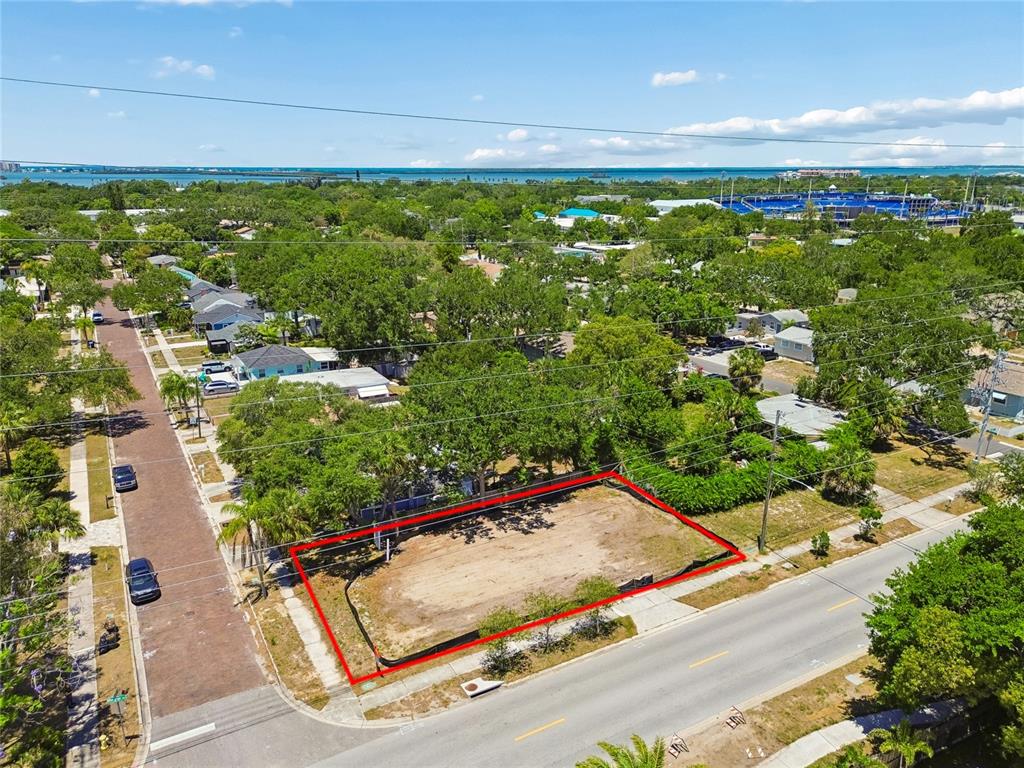 An aerial view shows a vacant, rectangular residential lot outlined in red on a corner — 558 ROANOKE STREET, DUNEDIN, FL