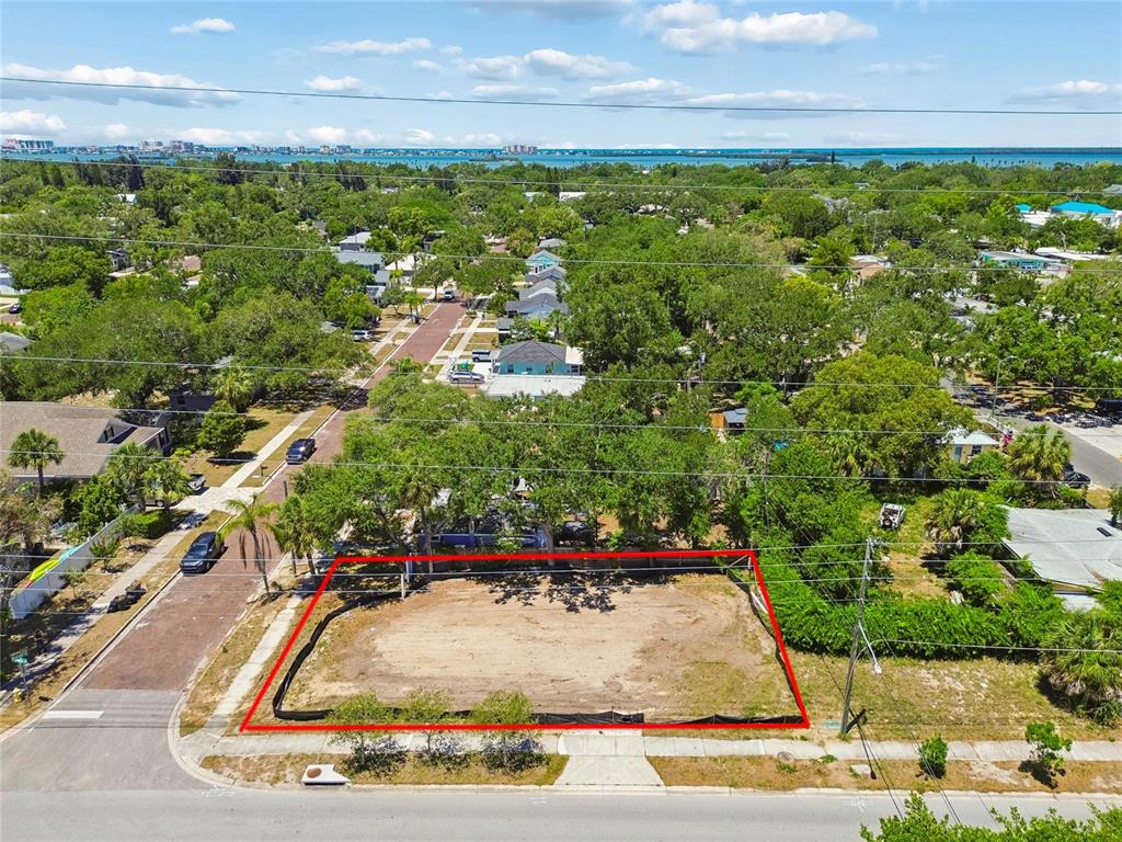 An aerial view shows a vacant, rectangular residential lot outlined in red along a street — 558 ROANOKE STREET, DUNEDIN, FL
