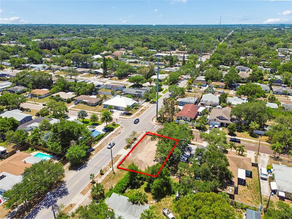 An aerial view shows a vacant, rectangular lot outlined in red along a residential street — 558 ROANOKE STREET, DUNEDIN, FL