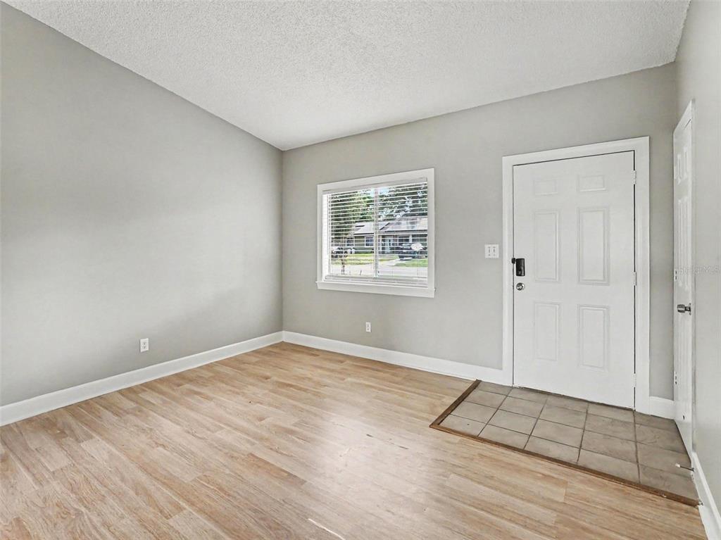 An empty room with light wood-look flooring, gray walls, a window, and a white door — 510 MOONBEAM ROAD, APOPKA, FL
