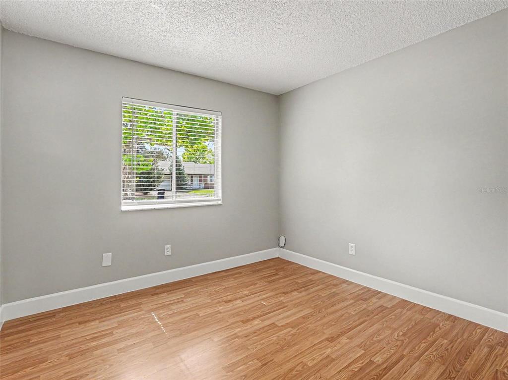 An empty bedroom features light gray walls, wood-look flooring, and a single window — 510 MOONBEAM ROAD, APOPKA, FL